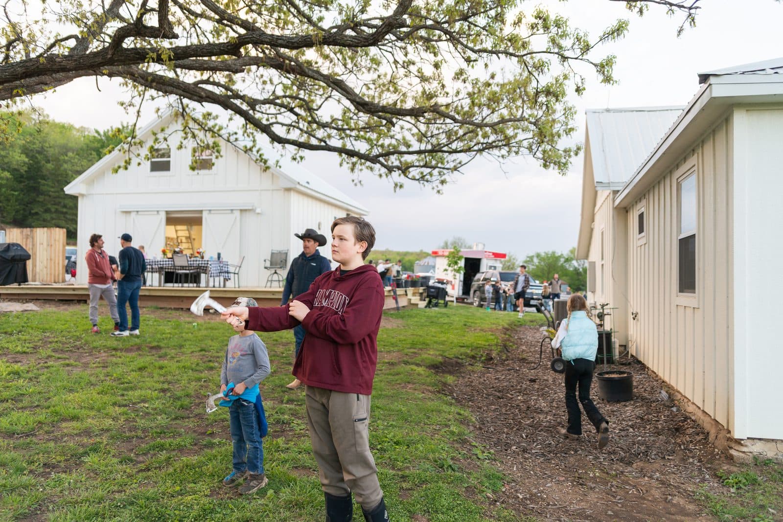 The farm during Country Kick Off — buildings, big oak, and families