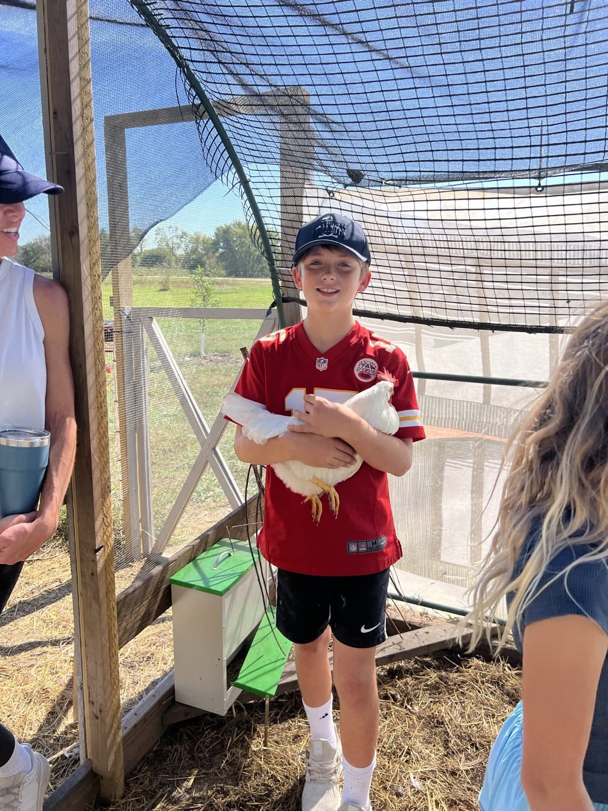 Kid holding a chicken in the coop