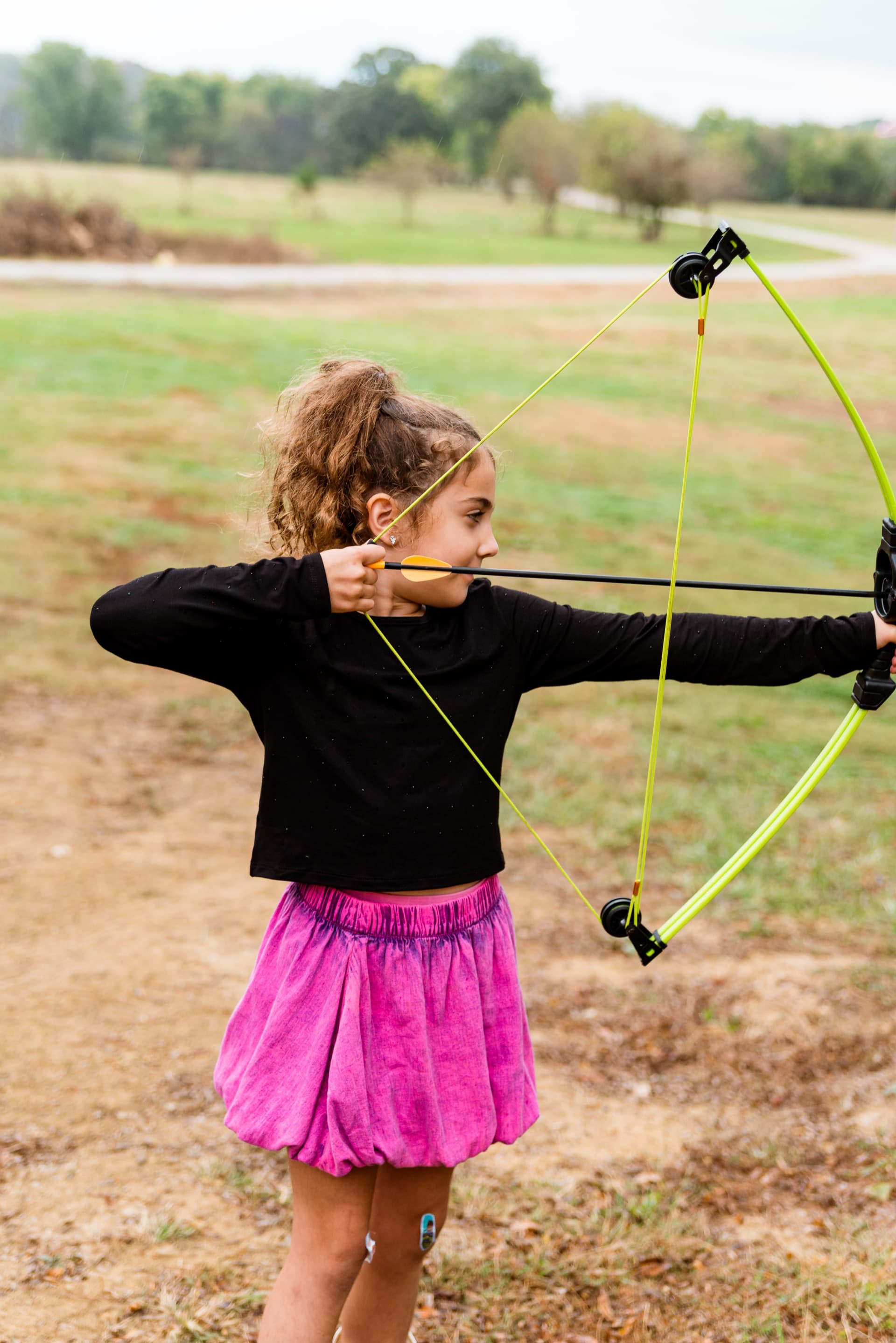 Girl drawing a bow in the Kansas hills
