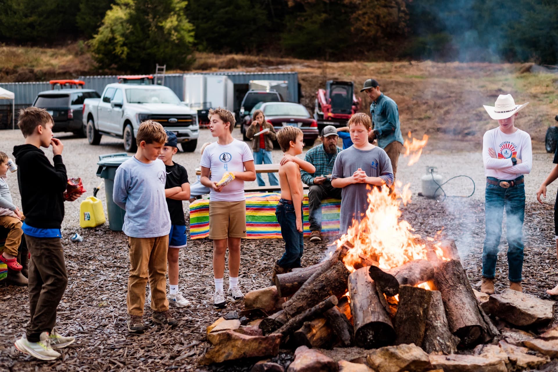 Kids and adults gathered around the campfire at dusk